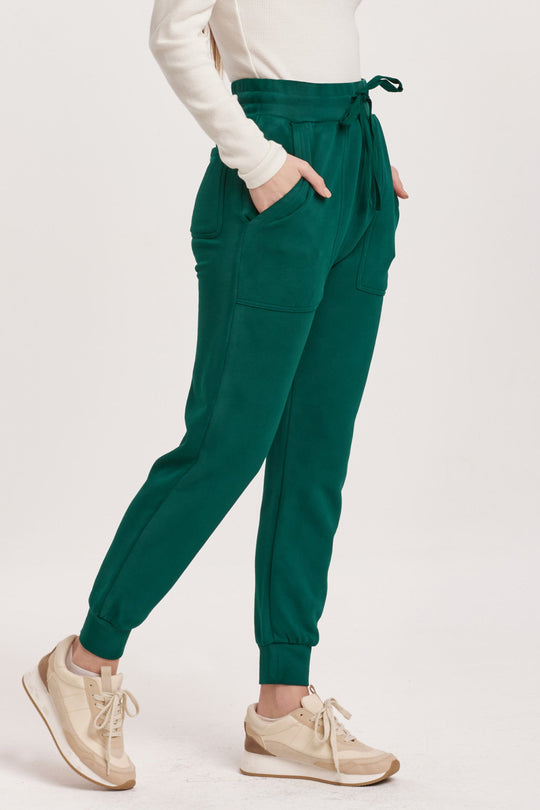 image of a female model wearing a DAHLIA HIGH RISE ANKLE JOGGER PANTS DEEP EMERALD DEAR JOHN DENIM 