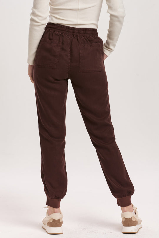 image of a female model wearing a JACEY SUPER HIGH RISE CROPPED JOGGER PANTS GROUND COFFEE DEAR JOHN DENIM 